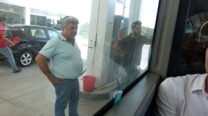 Our driver (left) watches while our attendant mans the pump. Photo taken from inside the bus.